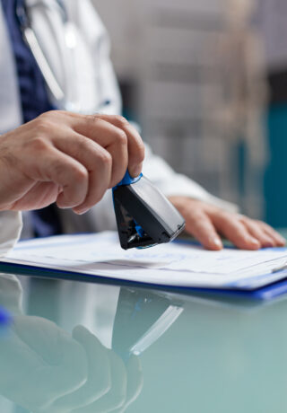 Doctor holding medical stamp to put on prescription paper